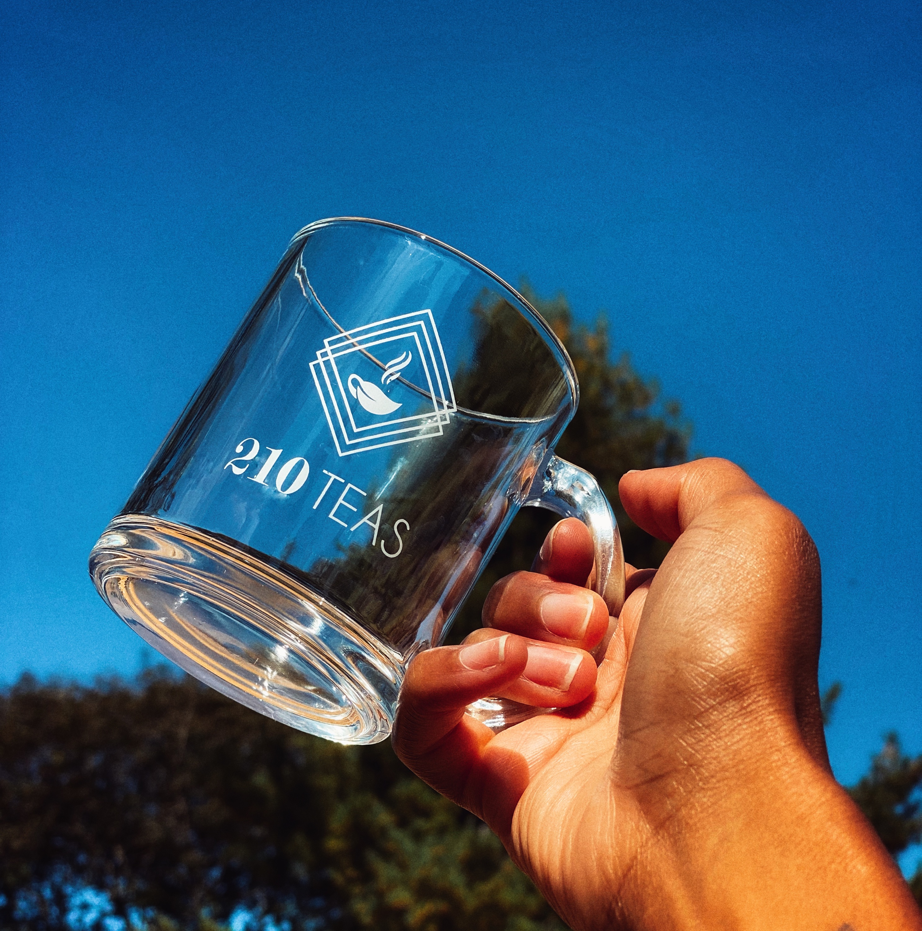 Picture of glass mug being held against blue sky